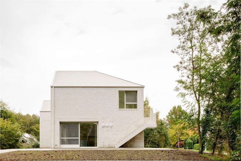 Pale brick facade with external staircase and gravel site under overcast sky