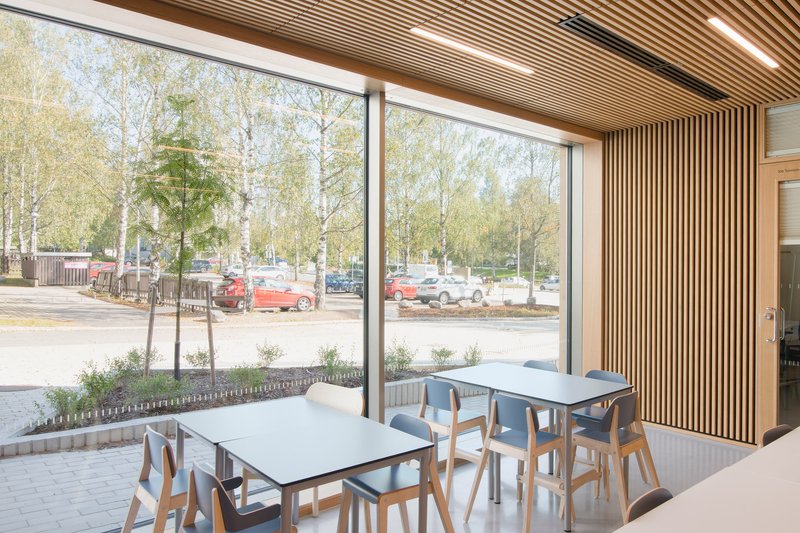 Dining area with timber slat wall, full-height glazing, and views of birch trees and parking