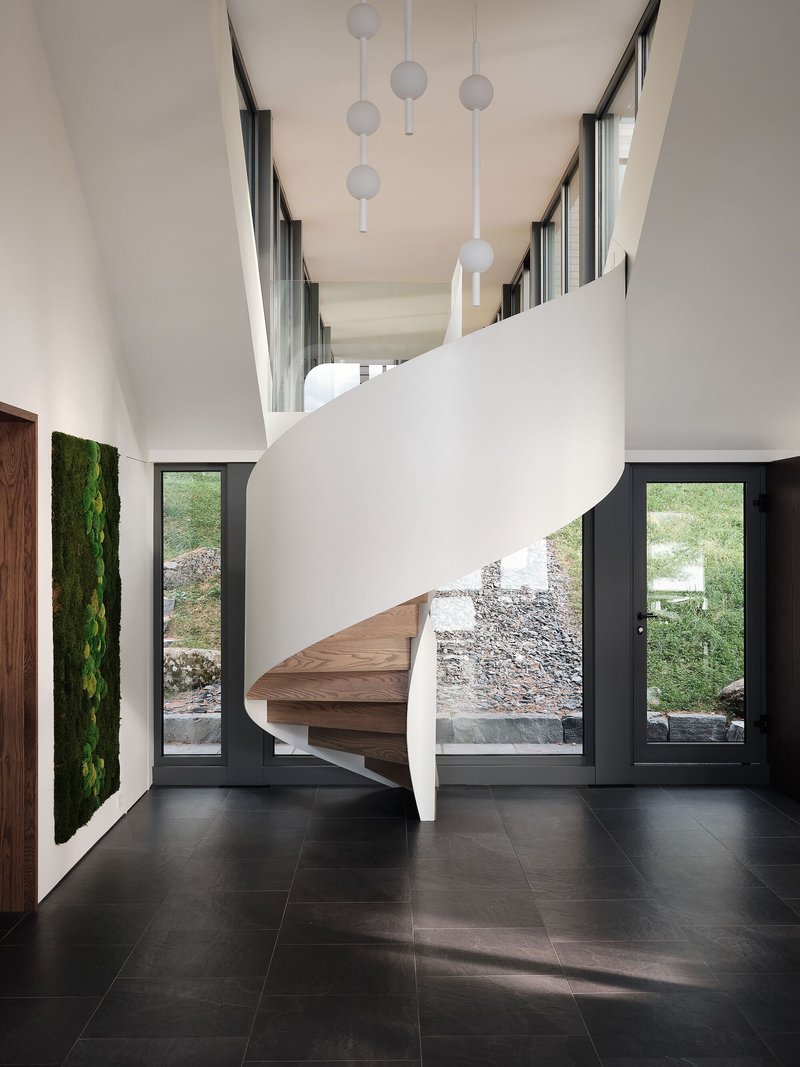 Helical staircase with timber treads and white balustrade beneath suspended globe pendants