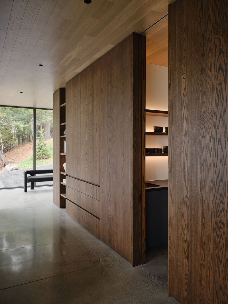 Built-in timber cabinetry with sliding panels and illuminated shelving along a polished concrete floor