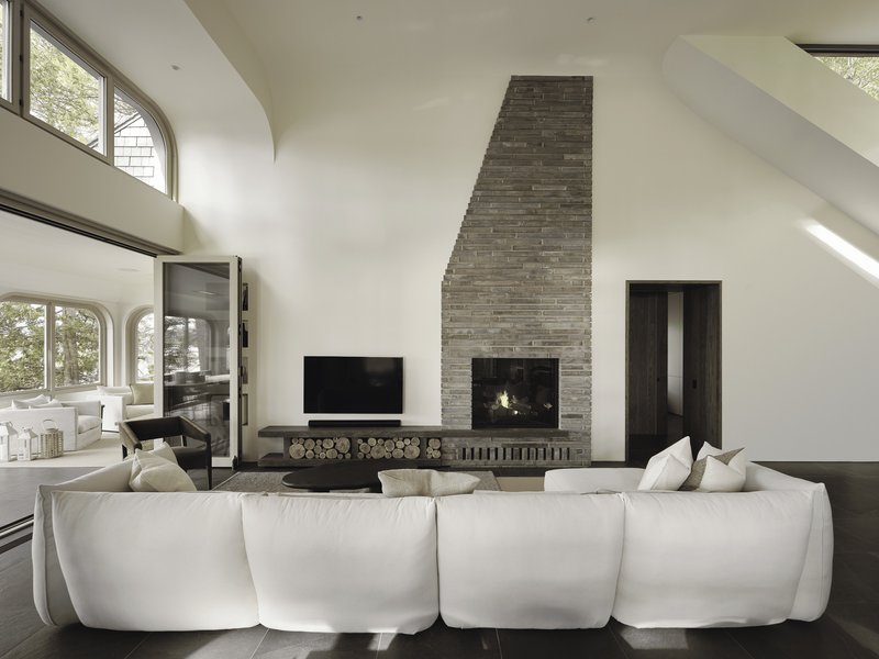 Vaulted living room with stacked brick fireplace, arched clerestory windows, and firewood storage niche