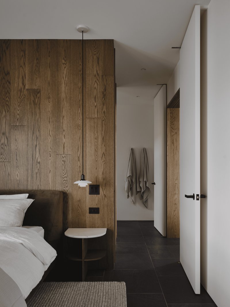 Bedroom with floor-to-ceiling oak paneling and pendant light beside the bed