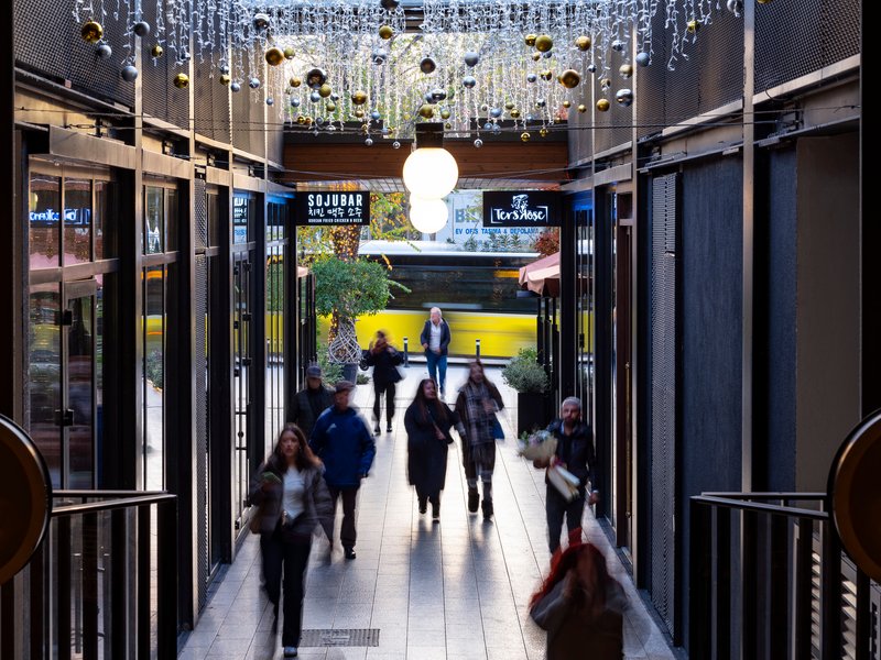 Axial view through perforated metal portal toward exterior courtyard with hanging sphere chandelier above