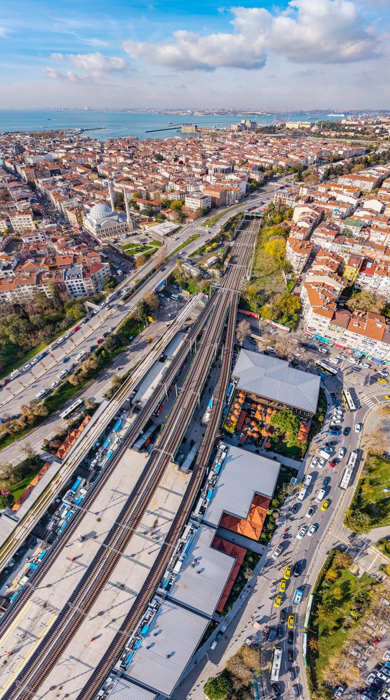 Aerial view of railway station complex with multiple platforms alongside residential neighborhoods and coastal bay
