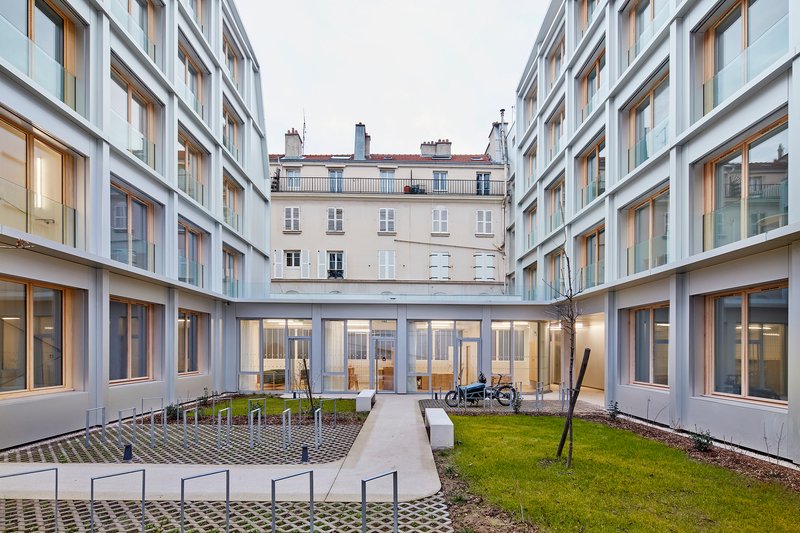 Courtyard view at dusk with glazed ground floor passage connecting two wings and bicycles parked outside