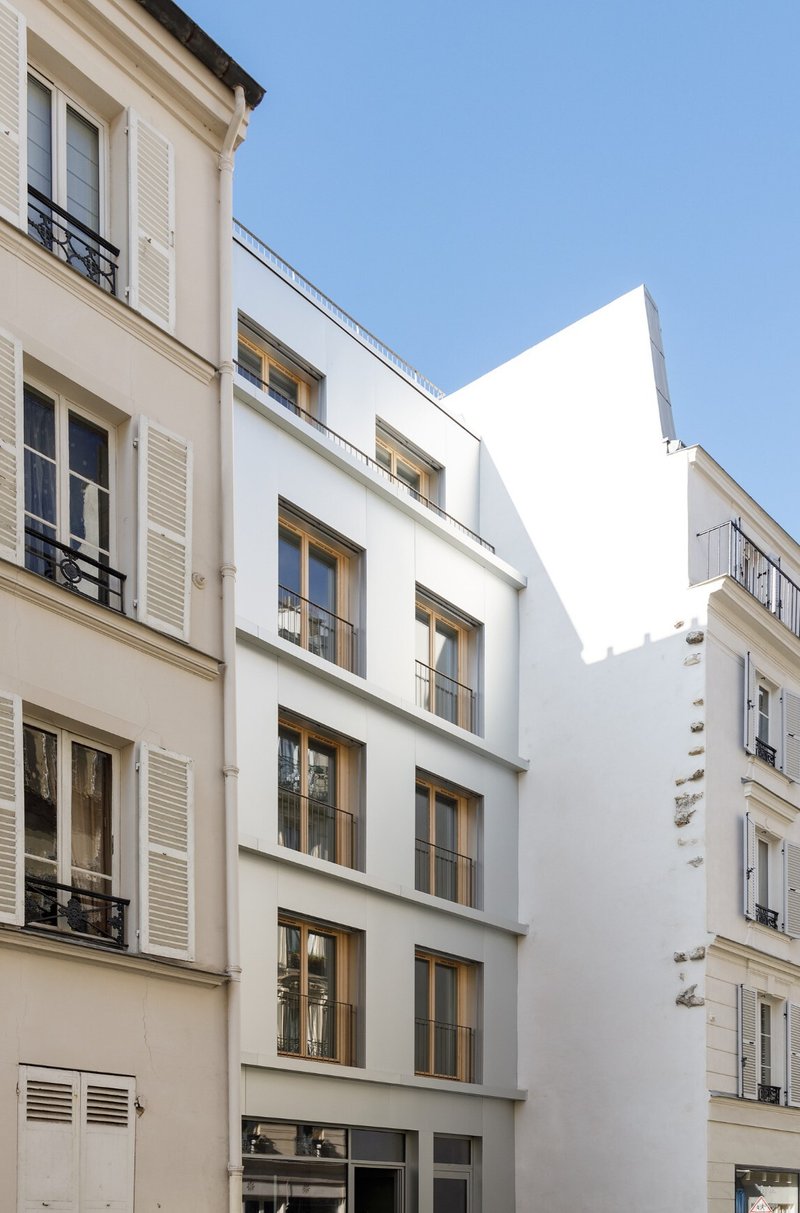 Street facade insertion between two existing buildings with four floors of timber-framed windows