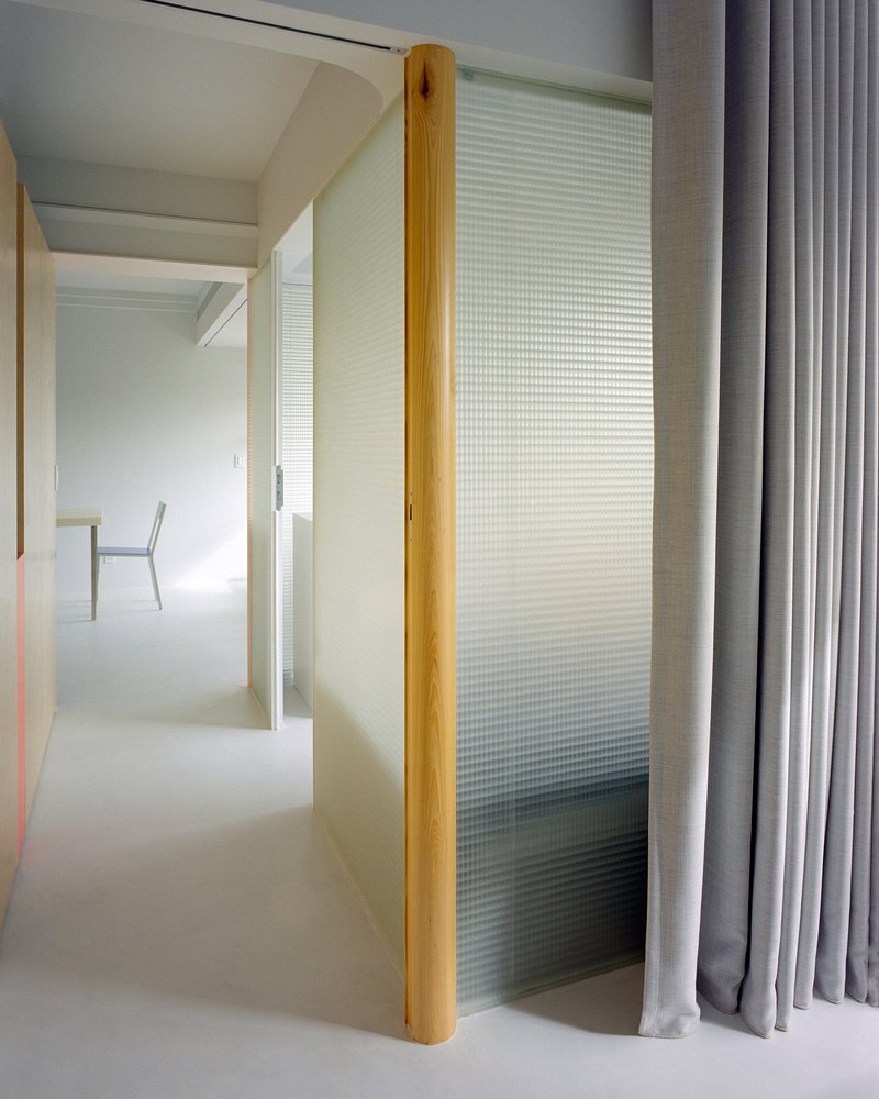 Sliding translucent panel with vertical timber edge and grey curtain drawn to one side