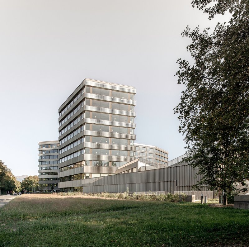 Multi-storey tower with louvered facade rising above a horizontal ribbed base in afternoon light