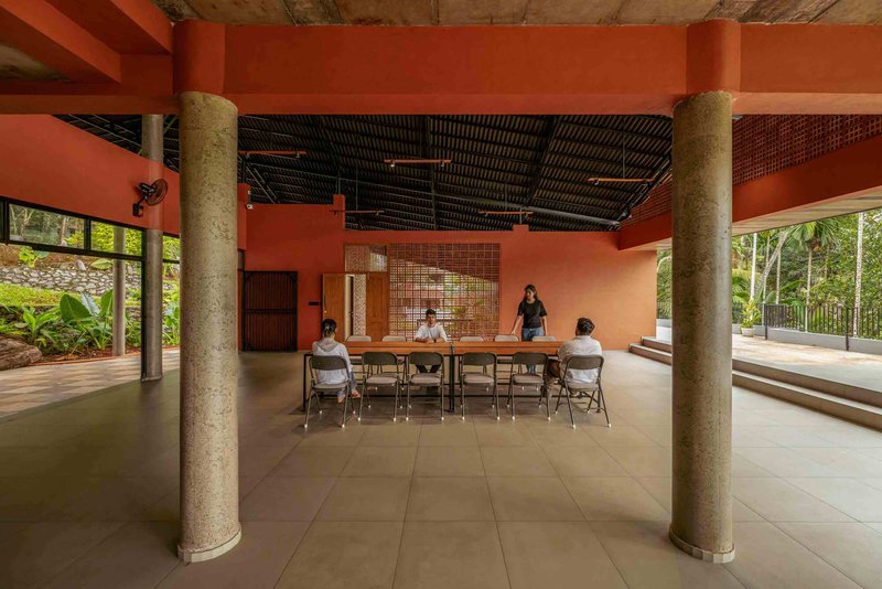 Open gathering space with cylindrical concrete columns and perforated brick screen wall framing seated group