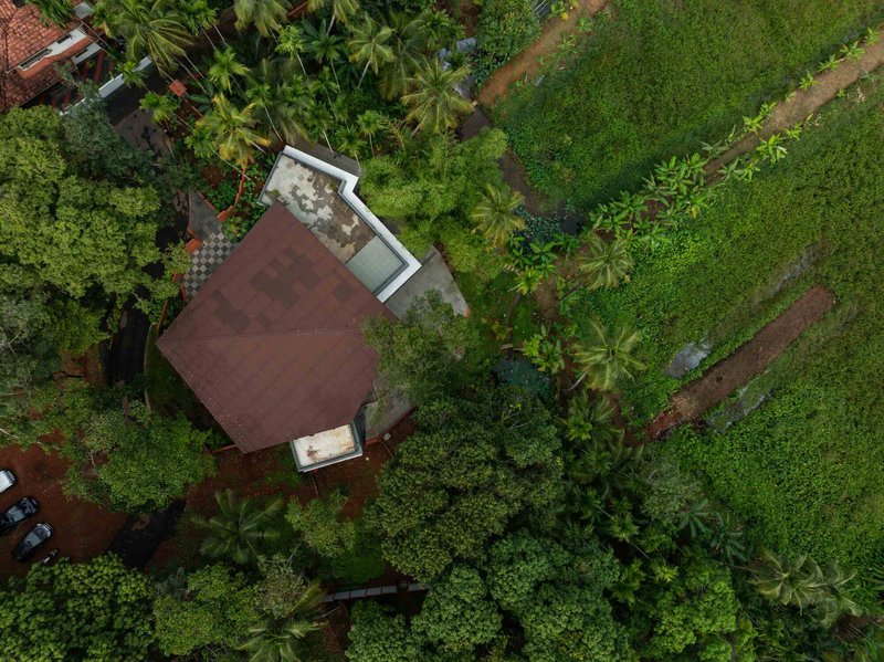 Aerial view of the pentagonal roof among coconut palms and verdant landscape