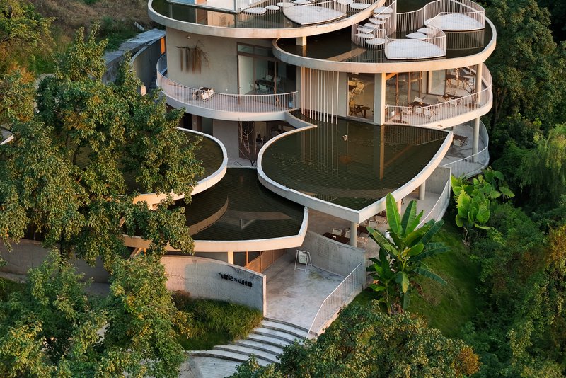 Close view of the undulating balconies with vertical railings and concrete terrace leading to entry steps