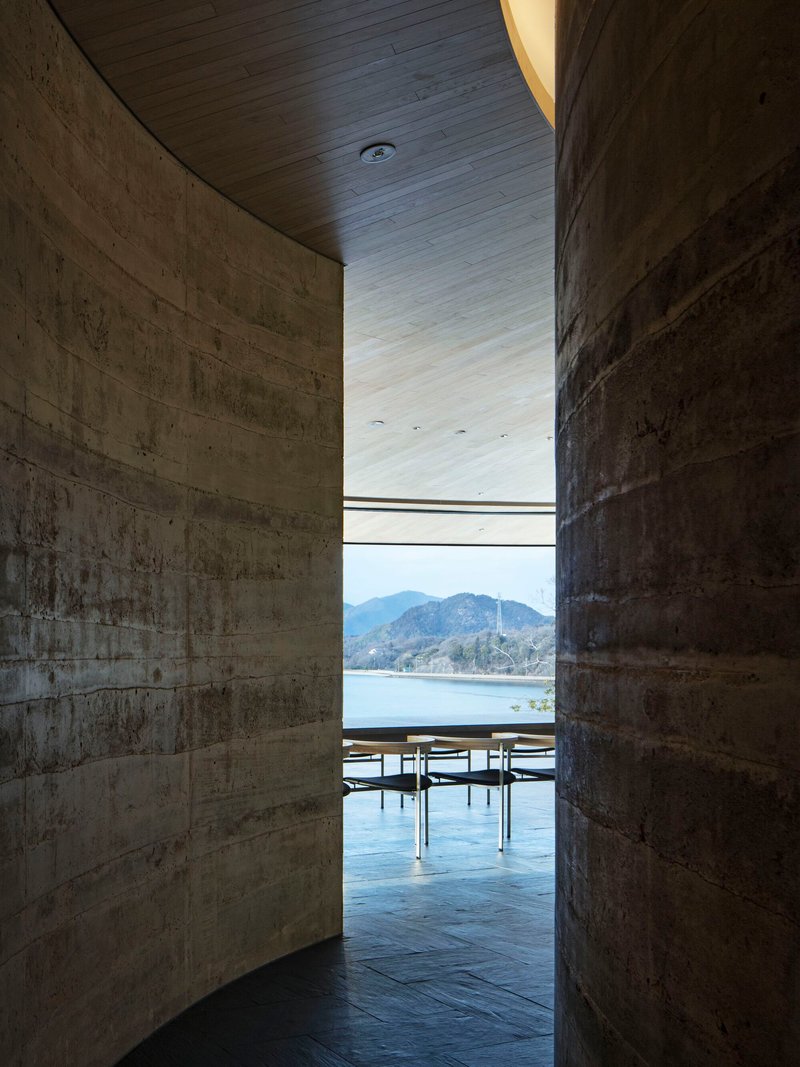 Concrete passageway framing a view of the lake and mountains through a horizontal slot window