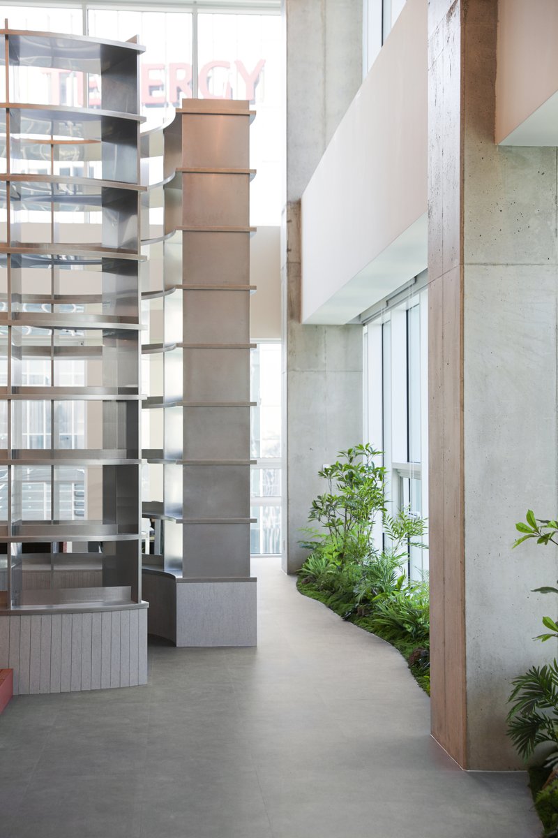 Interior walkway with planted bed along glass walls and board-formed concrete surfaces