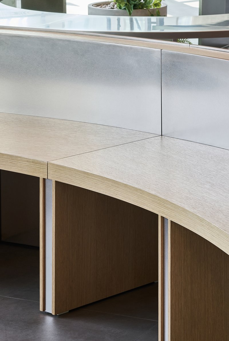 Detail of curved plywood desk edge with metal screen panel and exposed laminated construction