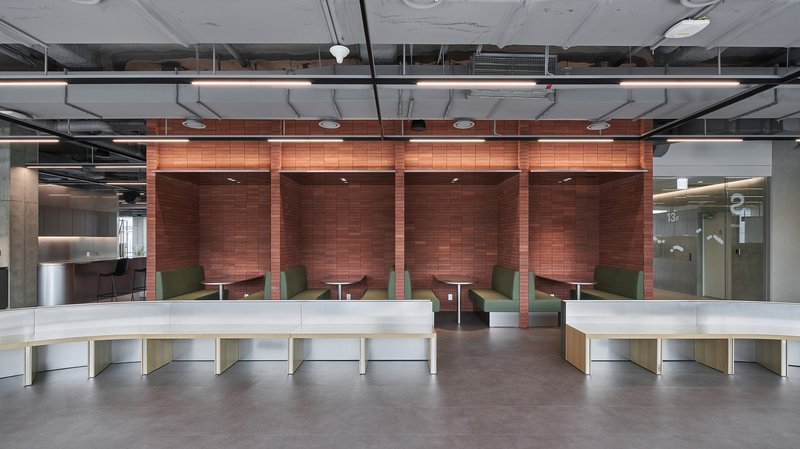 Booth seating area with copper tile alcoves and curved white counters under exposed ductwork