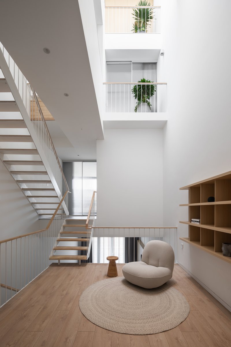 Multi-level interior with open timber stairs, metal railings, and small planted balconies in the void above