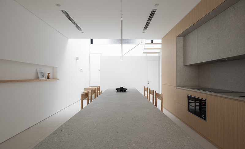 View down the length of the terrazzo dining table with clerestory light above