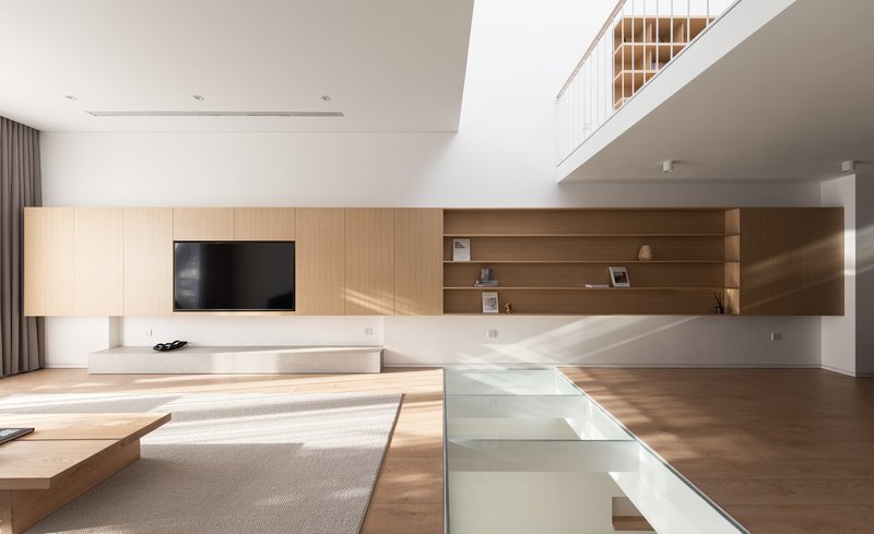 Living room with timber wall unit and sunlight streaming across the wood floor