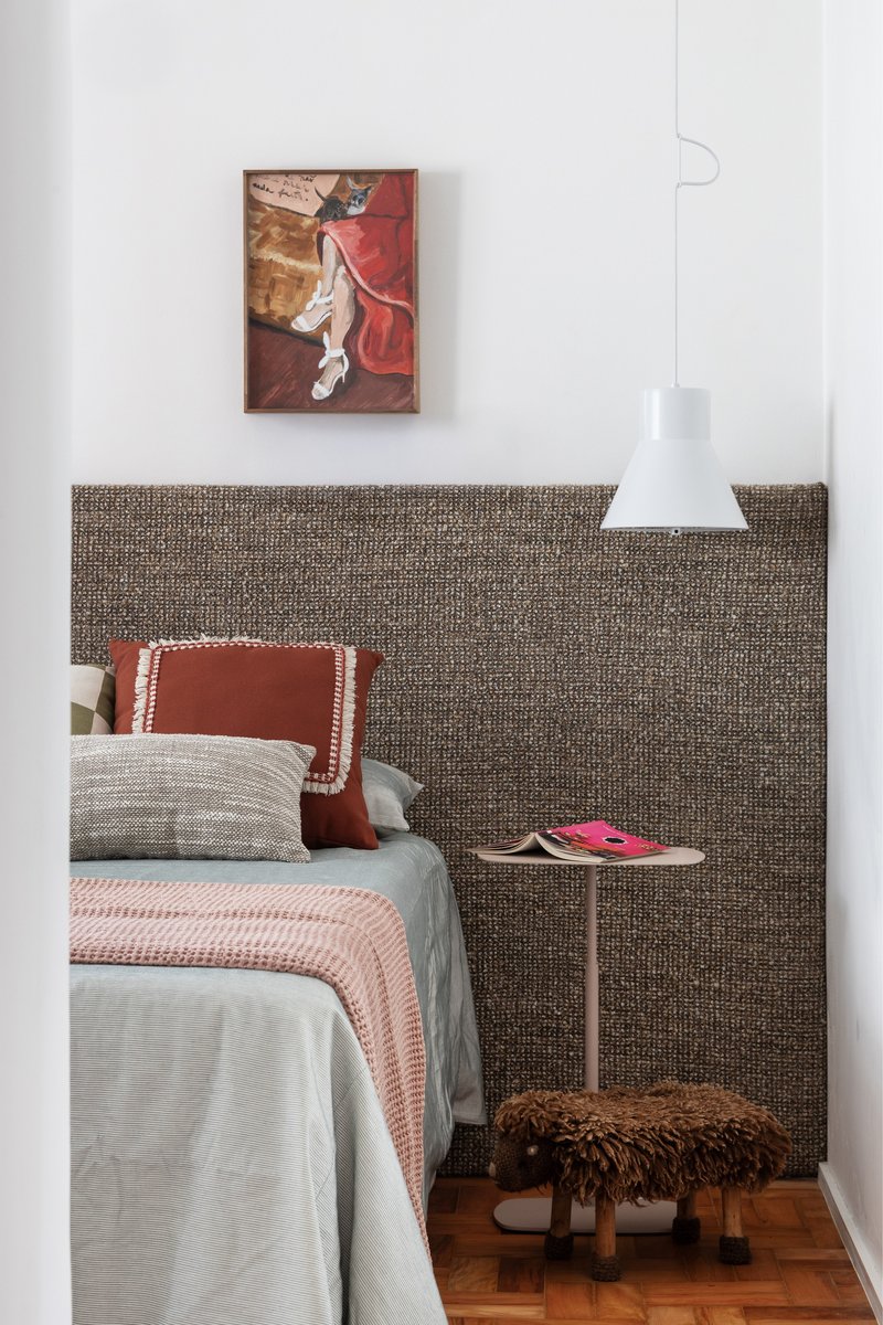 Bedroom with woven textile headboard panel and painting above the bed