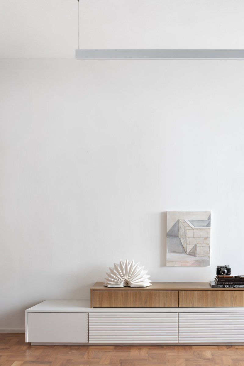 Low storage unit with timber and white panels beneath a white wall with pendant light