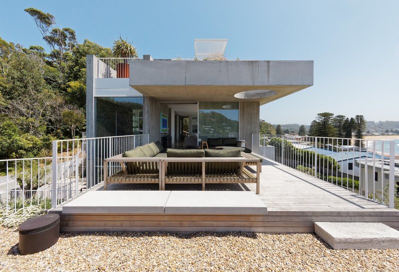 Roof deck with timber seating and white railing overlooking coastal vegetation and distant bay