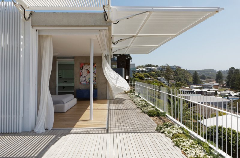 Corner of the timber deck terrace with white fabric canopy billowing in afternoon breeze