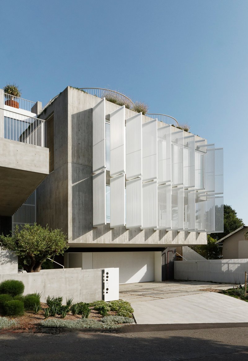 Side elevation showing the ribbed white facade stepping back above exposed concrete cores and planter boxes