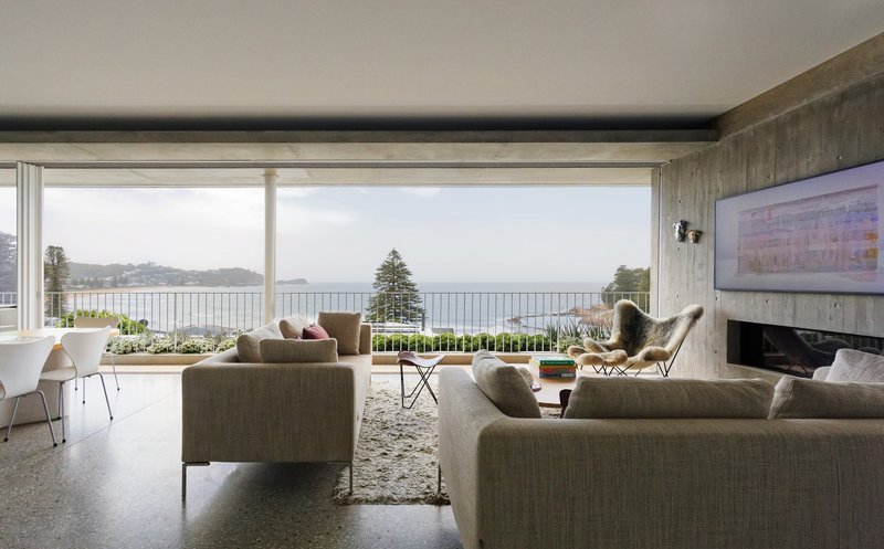 Living room with polished concrete floor and full-height glazing framing coastal views