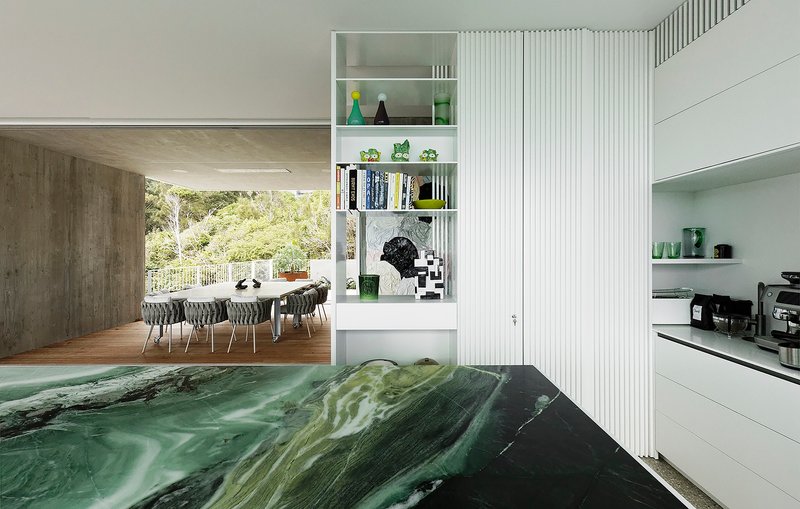 View through the kitchen island toward the dining area with ribbed white partition wall