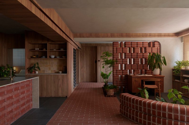Open-plan living space with patterned red brick divider walls and timber joinery under soft ambient light