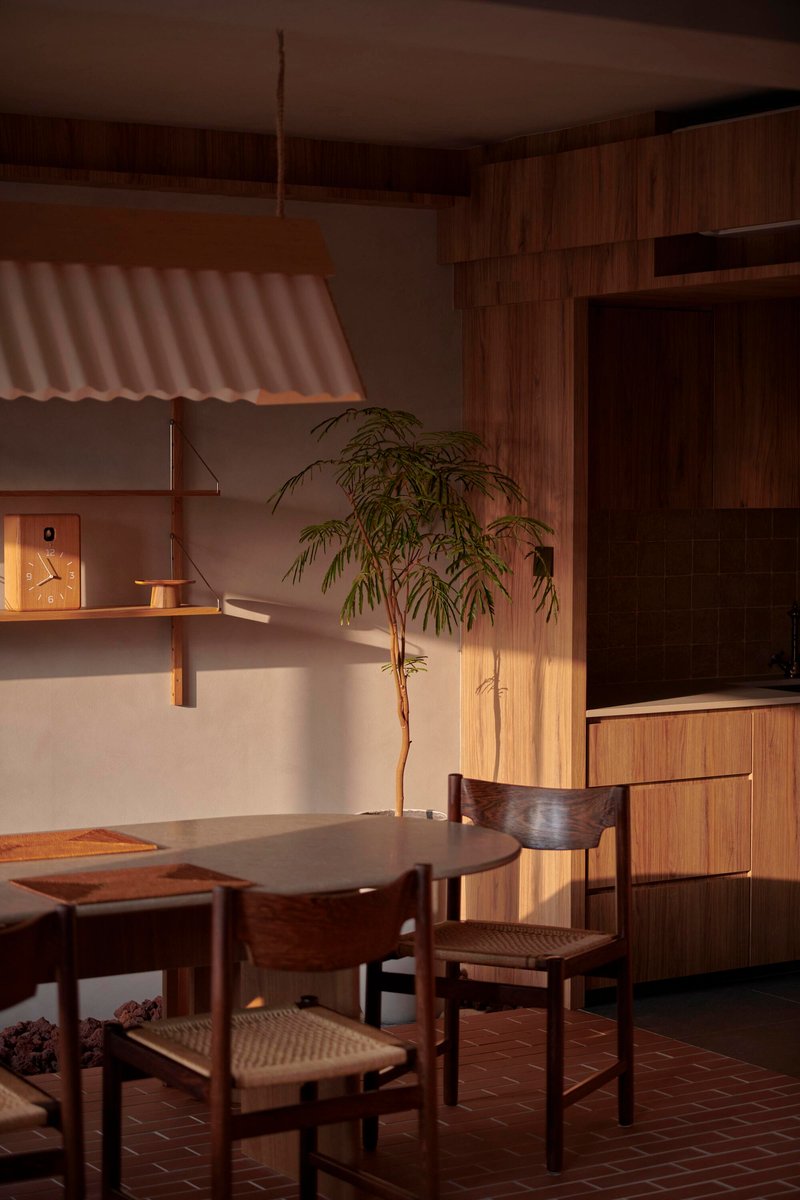 Dining table with woven-seat chairs beneath a corrugated pendant lamp at dusk