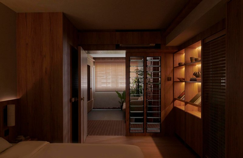View through timber-paneled bedroom toward corridor with horizontal blinds and built-in shelving