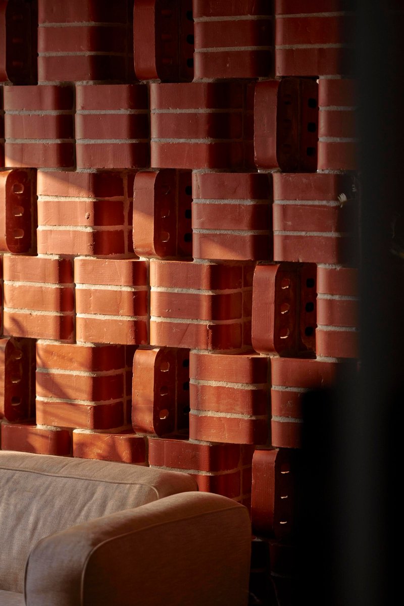 Textured brick wall corner with alternating solid and perforated units in warm afternoon light