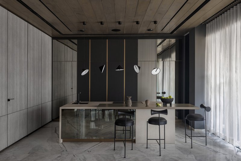 Kitchen with pale timber island, black bar stools, suspended disc pendants and concrete ceiling