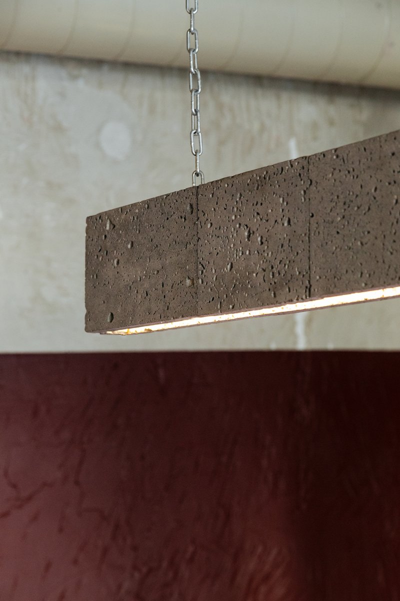Suspended rectangular pendant light fixture in textured brown concrete with integrated linear illumination
