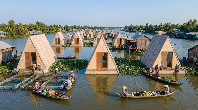 Aerial view of triangular floating shelters with timber louvers on a river surrounded by boats and residents