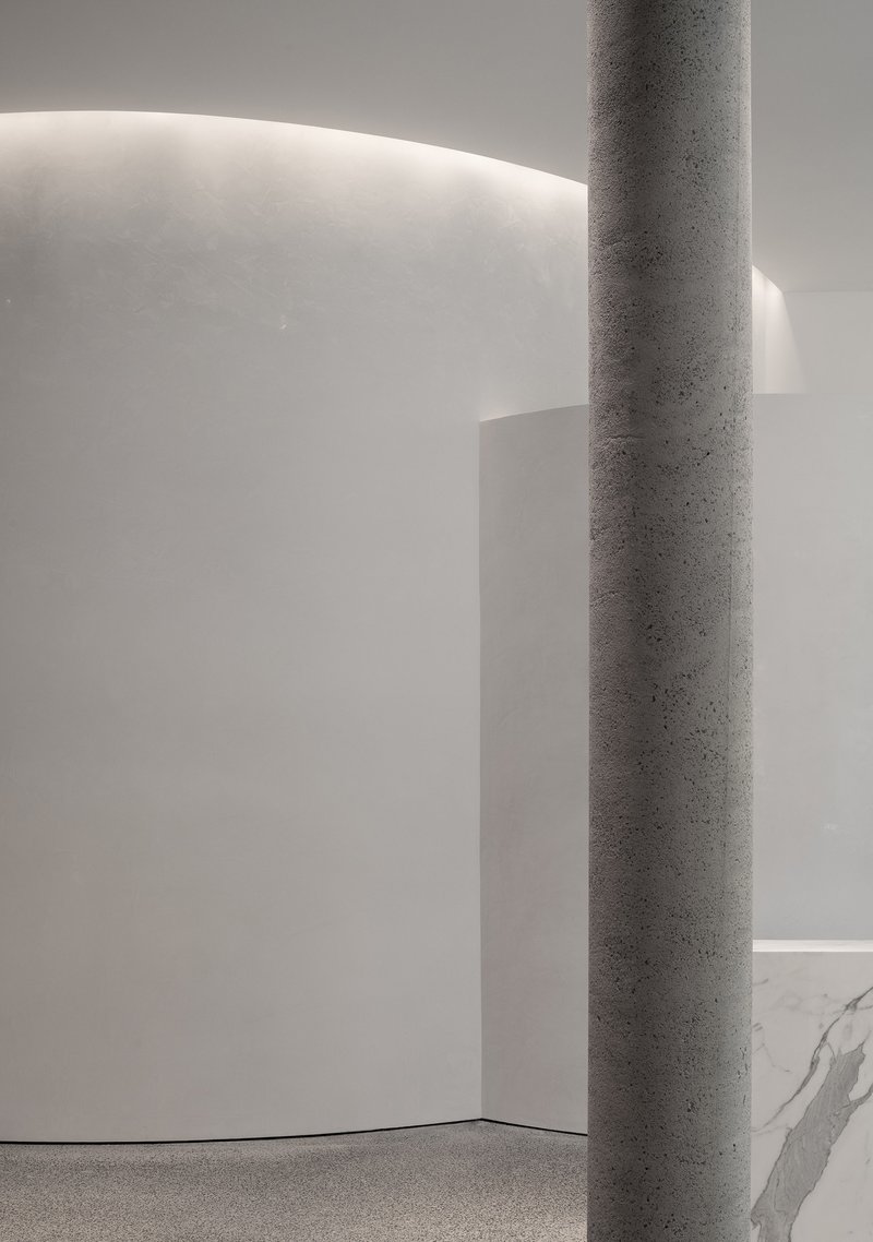 Detail of a terrazzo column against a curved white wall with cove lighting washing the surface