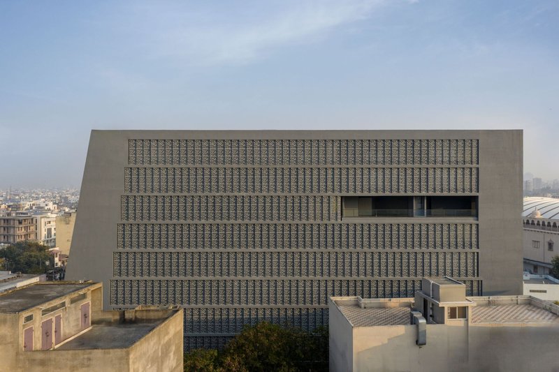 Head-on view of the gridded screen facade with rectangular window openings punctuating the pattern