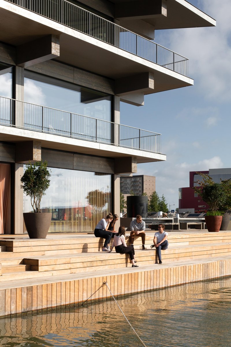 Timber deck terrace with people seated as the water edge meets the floating platform