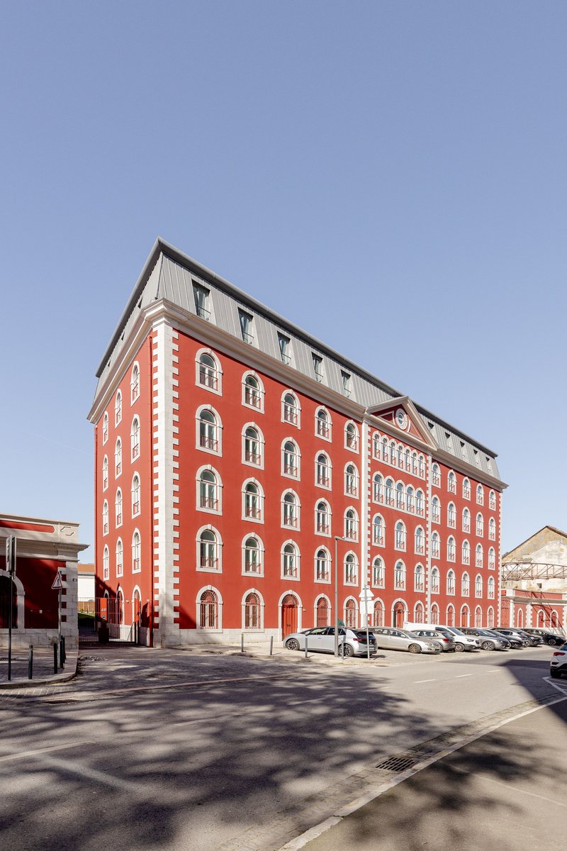 Red brick facade with white quoining and arched windows topped by a gray metal penthouse addition