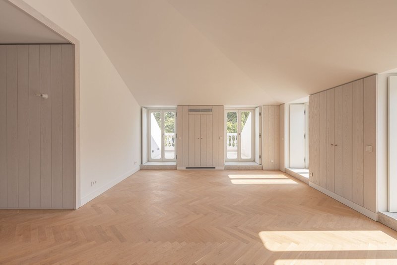 Room with sloped ceiling and light wood built-in cabinetry flanking central window