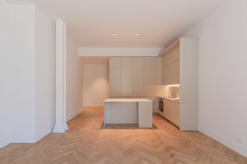 Compact kitchen with island and recessed lighting beneath dropped ceiling and herringbone oak flooring