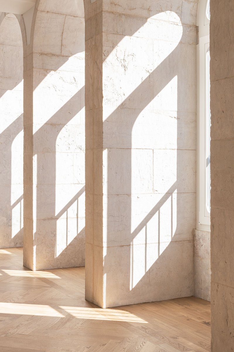 Close view of stone pier beside arched opening with bright sunlight casting diagonal shadows