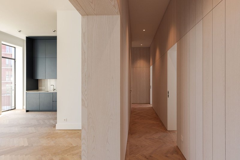 Hallway lined with timber-veneer panels and pale oak ceiling connecting rooms with herringbone wood floors