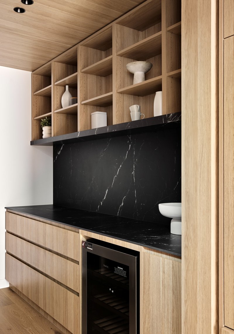 Timber open shelving above black marble counter with built-in wine refrigerator