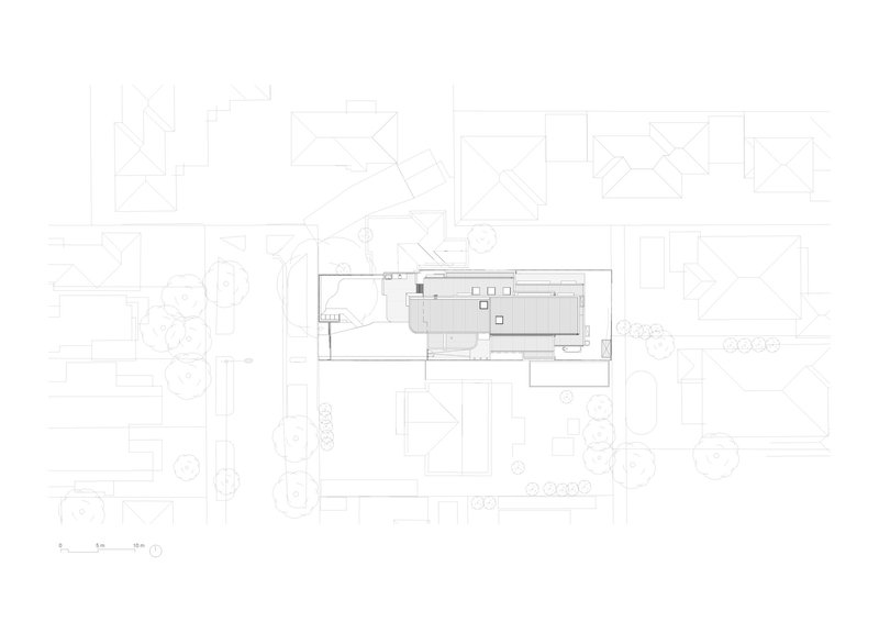 Site plan drawing showing a narrow rectangular building footprint surrounded by neighboring structures and landscape elements