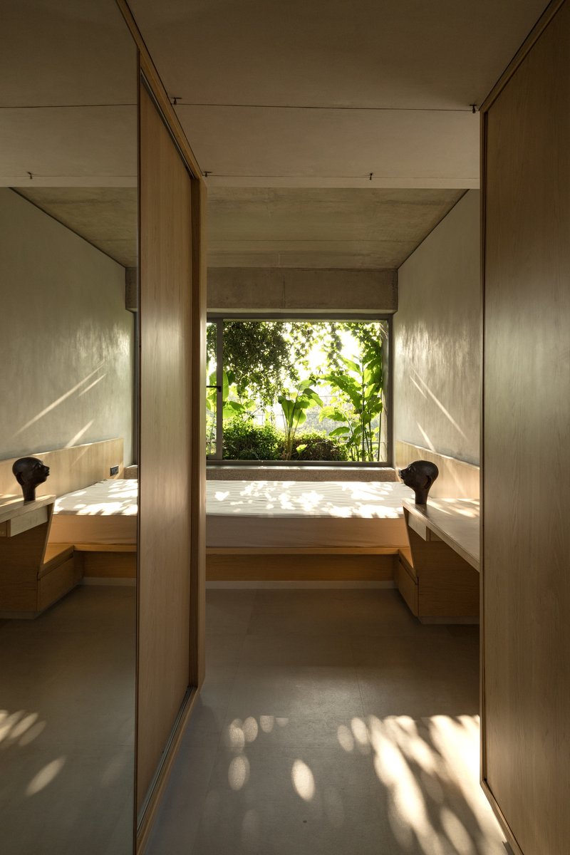 Narrow hallway with timber-clad walls and built-in seating flanking a window opening to dense foliage