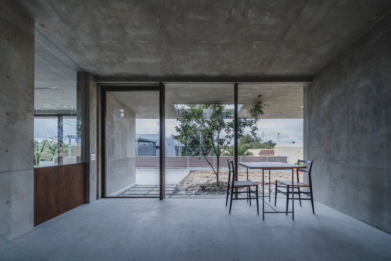 Living space with sliding glass doors framing view of interior courtyard with planted tree