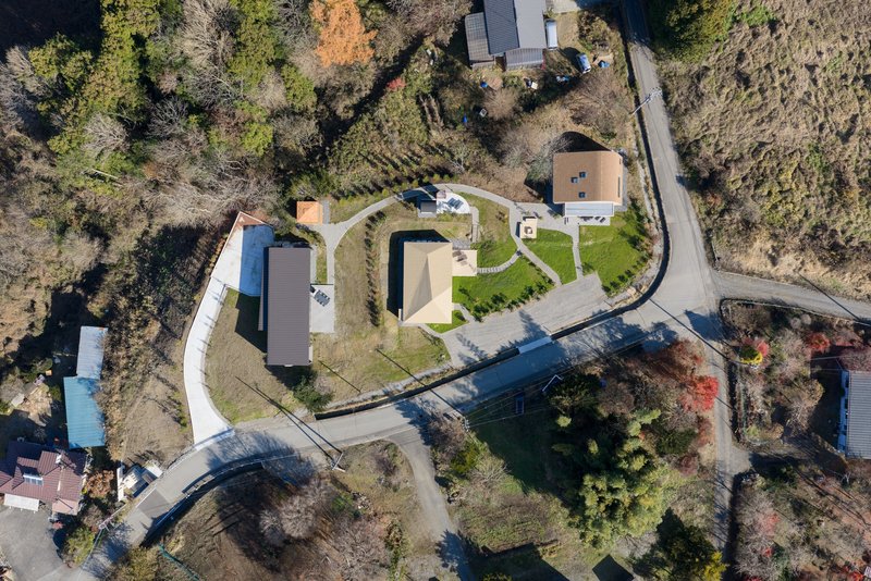 Aerial view of curved residential compound with planted beds and winding pathways among bare trees