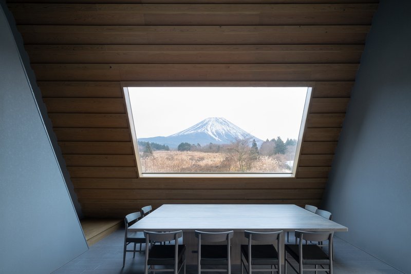 Dining table beneath a rectangular skylight framing view of snowy mountain